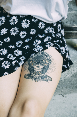 Street style hipster woman with artistic body tattoo on her leg closeup. Outdoor youth and lifestyle concept.の写真素材