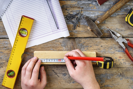 Carpenter working with crafting tools in his workshop. Top view of man's hands measuring on working desk.の写真素材