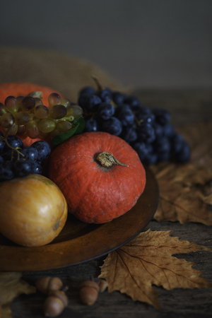 Happy thanksgiving holiday concept. Still life of autumn leaves, pumpkin, and fruits on rustic wooden table.の写真素材
