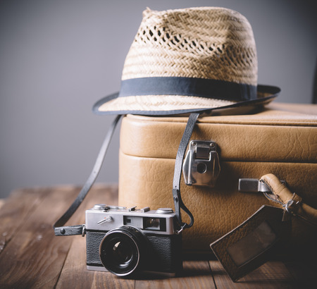 Vintage case, hipster hat, and retro camera on wooden background still life. Summer holiday vacation and adventure traveling concept with copyspace.の写真素材