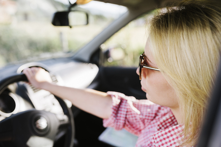 Young blond woman with sunglasses driving car. Casual hipster girl driver travel in vehicle.の写真素材