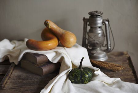 Autumn still life with vintage lantern and pumpkin vegetable on rustic wooden table.の写真素材