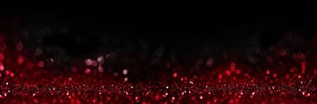 Abstract blur red glitter on black background. Card for Valentine's day, christmas and wedding celebration. Love bokeh sparkle confetti textured layout. Classy elegant design.の写真素材
