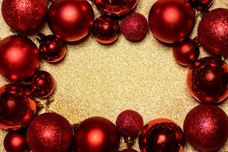 Red Christmas and New year background with christmas bauble frame on golden glitter texture with...