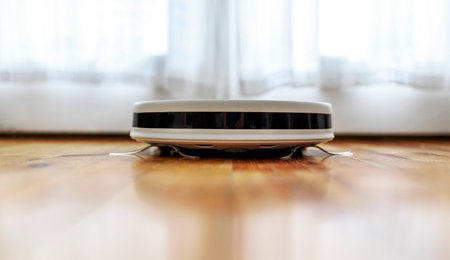 Robot vacuum cleaner and mop cleaning living room floor closeup. Modern smart device for everyday housekeeping.の写真素材