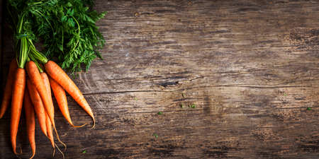 Top view of fresh organic carrot roots on wooden textured kitchen table. Cooking food background banner with copyspaceの写真素材