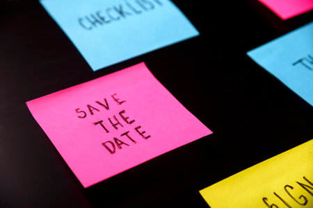 Colorful sticky notes on black board reminder. Save the date written sticker on pineboard. Remember...