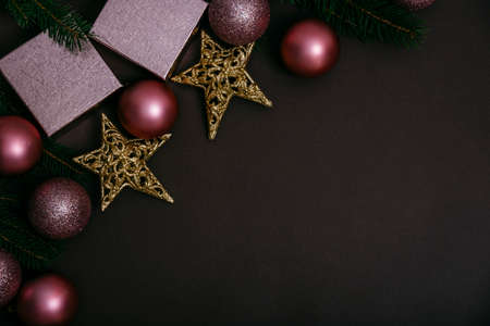 Pink christmas balls on brown background top view. Shiny christmas baubles, present box and fir tree...