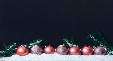 Pink christmas balls with snowflakes on dark brown wall. Elegant Christmas decoration background. Minimal trendy greeting card. Merry christmas and happy new year.の写真素材