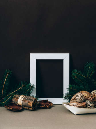 Empty photo frame on brown wall with organic christmas decoration. Styled winter holiday image....