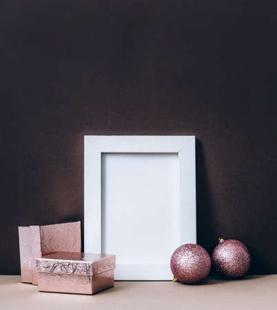 Empty photo frame on brown wall with pink christmas decoration. Styled winter holiday image. Elegant...
