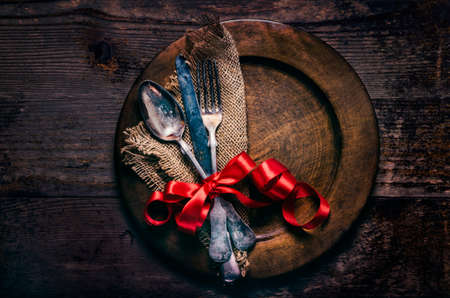 Valentines dinner setting with vintage silverware, dinner plate and red ribbon on wooden table....
