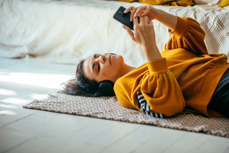 Single woman in her 40s relaxing in her cozy home interior and have leisure time alone with music streaming and online browsing. Autumn lifestyle indoor.の写真素材