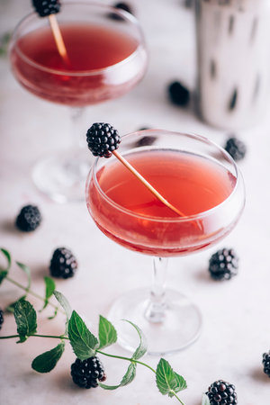 Blackberry gin cocktail in martini glass garnish with fruit on luxury marble table. Beverage liquor for classy dinner party.の写真素材
