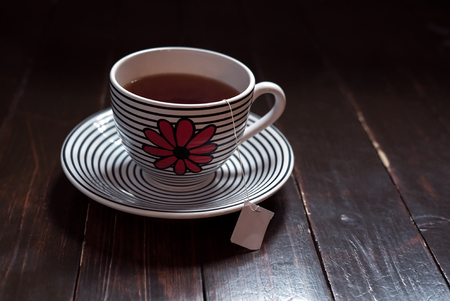 Green tea and teabag inside a big cup with saucer on vintage woodの写真素材