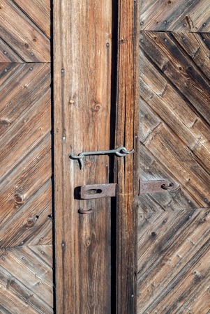 Closeup of an old rusted lock on a rustic rural door with decorative natural weathered wood planks with antique varnish - Vintage aged wooden barn exterior in the countrysideの写真素材