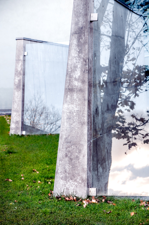 Modern public architectural attraction of cement and windows with reflected tree silhouette and clouds in autumn scenery - Contrasts of cool urban design buildings and fall nature in sundownの写真素材