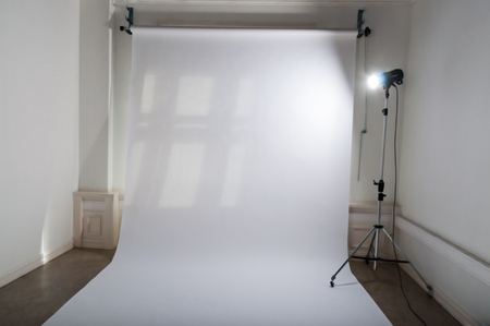 An empty professional photo studio with clean and simple photographic equipment setup of white,...