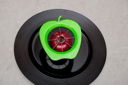 A green modern apple cutter with an organic, red healthy apple full of natural vitamins and...