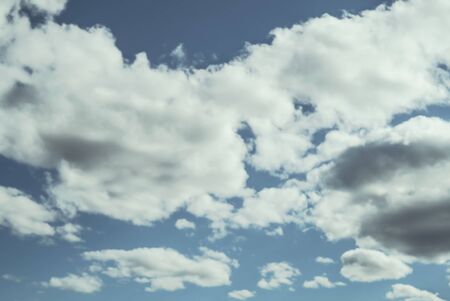 Looking up at a blue overcast summer sky with fluffy, soft white clouds - Concept of daydreaming, weather or meteorologyの写真素材