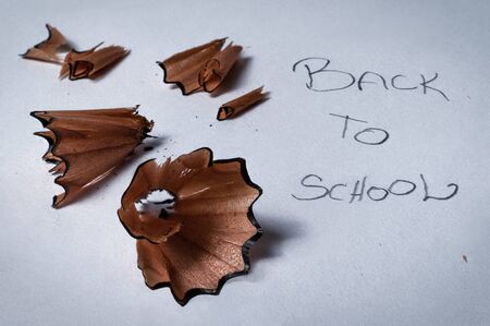Closeup macro detail of pencil sharpener wooden swirl shavings on with written text back to school -...