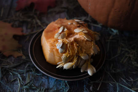 Closeup of orange pumpkin inside clean out with many seeds on a rustic table and black plate in preparation for making a jack-o-lantern halloween or thanksgiving holiday decorationの写真素材