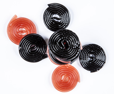 red and black licorice wheels on a white の写真素材