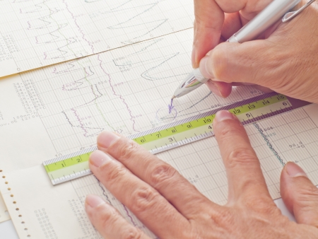 pen and ruler on hand examining scientific graph to analysis the results