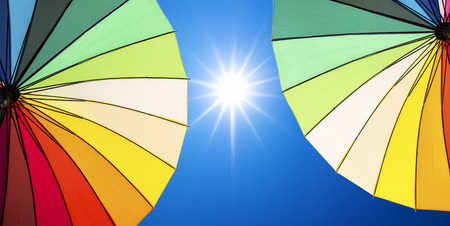 colorful umbrella on blue sky background with the sunの写真素材