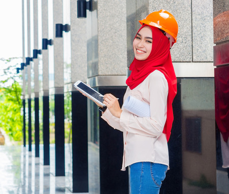young Muslim woman wearing a protective helmet standing on the column backgroundの写真素材