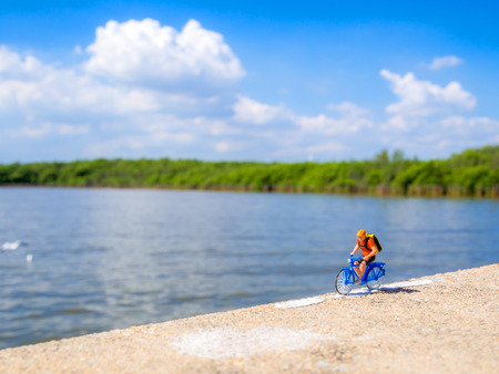 plastic toy in the cycling action in front of the sea with beautiful skyの写真素材