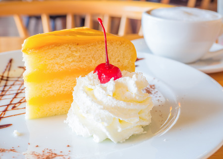 cherry topping on whipping cream served with orange cakeの写真素材