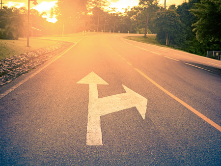 white arrow points direction to the curve asphalt roadの写真素材
