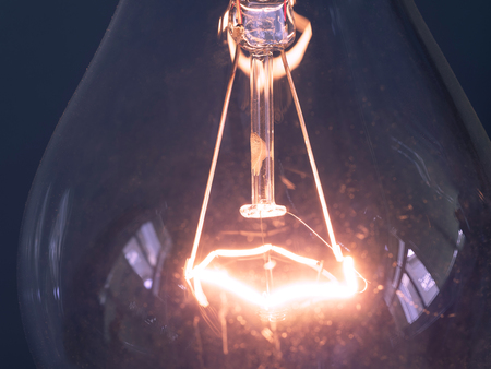 close up of glowing element in the incandescent light bulb, showing hot wire glow by electric...