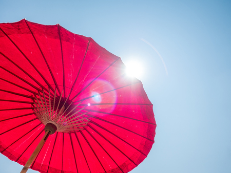 red paper umbrella against sunny sky backgroundの写真素材