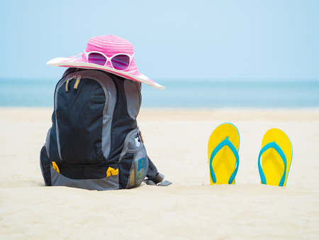 backpack, sandal footware, straw hat, and sun glasses on the sand beachの写真素材