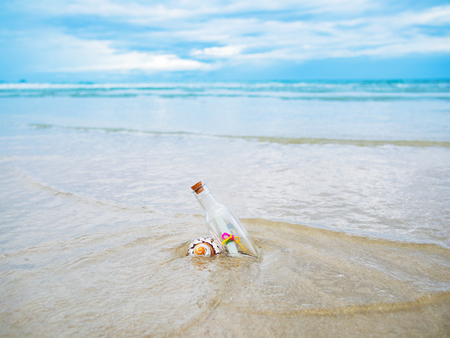 message paper inside the clear glass bottle on the sand coast of the seaの写真素材