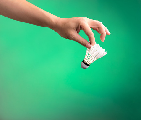 badminton sport , white shuttlecock hold by player's hand on green backgroundの写真素材