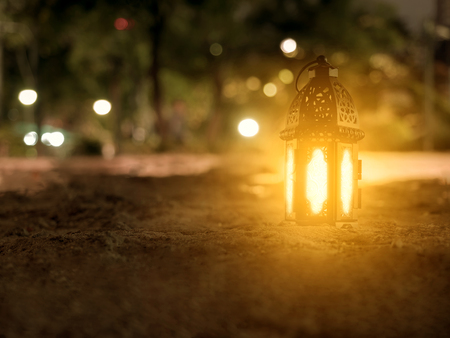 lighting with candle inside Lantern shining on sand floor playground, children play with it in...