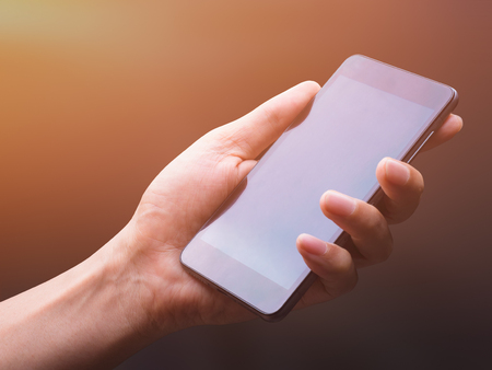 human hands holding a smartphone in many action on black background, with clipping path,  light leak addedの写真素材