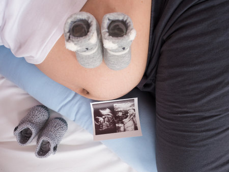 pregnant Woman holding her hands tender on her baby with preparation stuffs. Maternity or motherhood conceptの写真素材