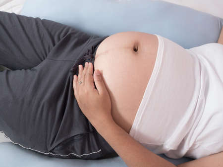 Pregnant women sleeping on bed by pregnancy related positionの写真素材