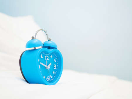 The vintage metal alarm clock on  the bedroom shows time in hour and minute needle on cyan...