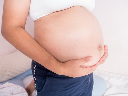 pregnant woman applying moisturizer on her belly with funny smile from moisturizing cream on her tummy. Maternity  or motherhood concept.の写真素材
