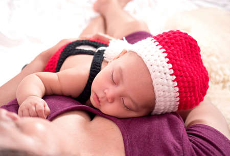cute four-month baby  santa  with Christmas red dress on white fabric background in lovely action, motherhood and christmas conceptの写真素材