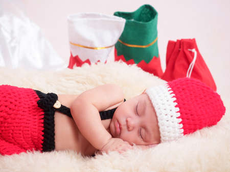 cute four-month baby  santa  with Christmas red dress on white fabric background in lovely action, motherhood and christmas conceptの写真素材