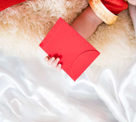 cute asian four-month baby in chinese traditional red dress sleeping with red envelope of money gift...