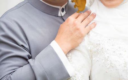 closeup shot of hands of bride and groom with wedding rings and bouquet in celebrating eventの写真素材