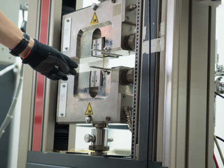 human hand point to tensile strength tester of pvc sample  using in the industrial construction. Strength property makes it  can be loaded heavy weight of mass.の写真素材