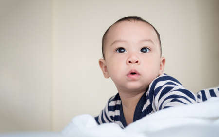 cute asian seven month male baby in black and white dress in bedroom at homeの写真素材